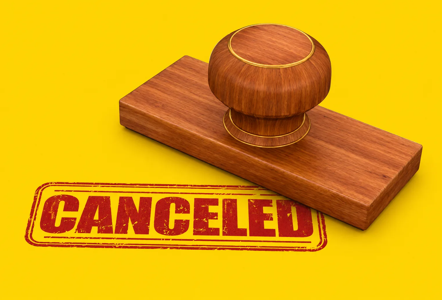 A wooden rubber stamp resting on a yellow background next to a red “CANCELED” mark freshly pressed beside it.